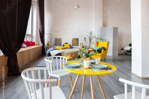 Trendy fashion luxury interior design in Scandinavian style of studio apartment with bright yellow furniture and decorated with new year lights.