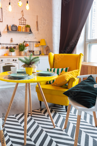 Trendy fashion luxury interior design in Scandinavian style of studio apartment with bright yellow furniture and decorated with new year lights.