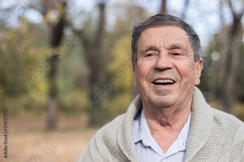 Portrait of happy senior man smiling, in the public park, outdoors.. Old man relaxing outdoors and looking away. Portrait of elderly man enjoying retirement