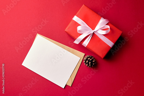 Greeting card mockup with gift box and pine cone on red background