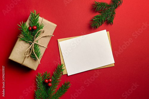 Christmas greeting card mockup with decorated gift box on red background © mikeosphoto