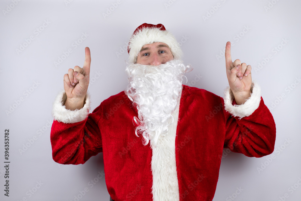 Man dressed as Santa Claus standing over isolated white background pointing up Man dressed as Santa Claus standing over isolated white background pointing up