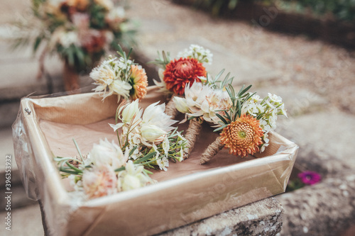 Photos button hole flowers in a paper lined basket