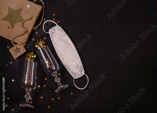 Wine glasses, gift bag, protective medical mask, gold sparkles on a black background.Place for signature.