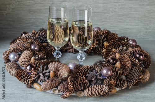 Wine glasses, Christmas wreath in a natural style on a gray background. Christmas composition.