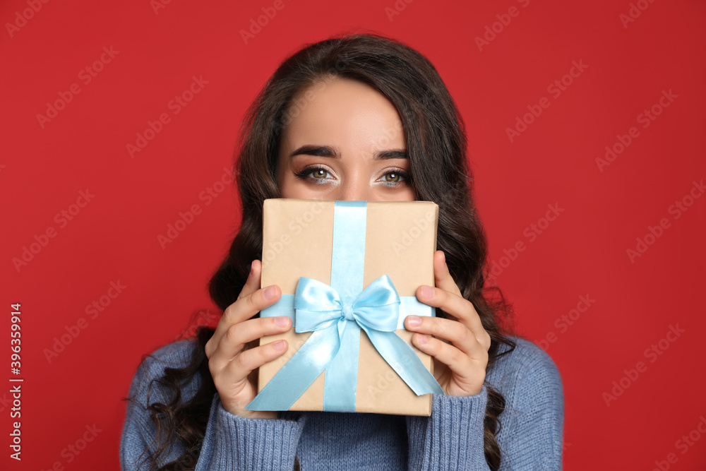 Beautiful young woman with Christmas gift on red background Beautiful young woman with Christmas gift on red background