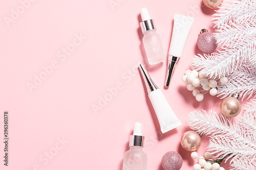 Set of winter skin care cosmetic such as creams, lotions and serums and Christmas decorations on light pink background with copy space for your text. Christmas cosmetic sale banner.