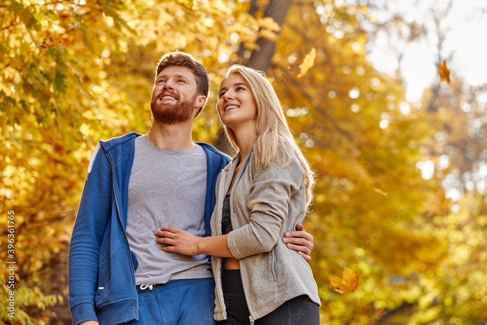 sportive married couple have leisure adventure time in the forest, stand in contemplation, looking up at yellow trees. at sunny autumn day sportive married couple have leisure adventure time in the forest, stand in contemplation, looking up at yellow trees. at sunny autumn day