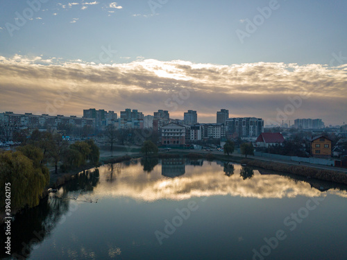 Aerial drone view. Reflection of the rising sun in the city lake.