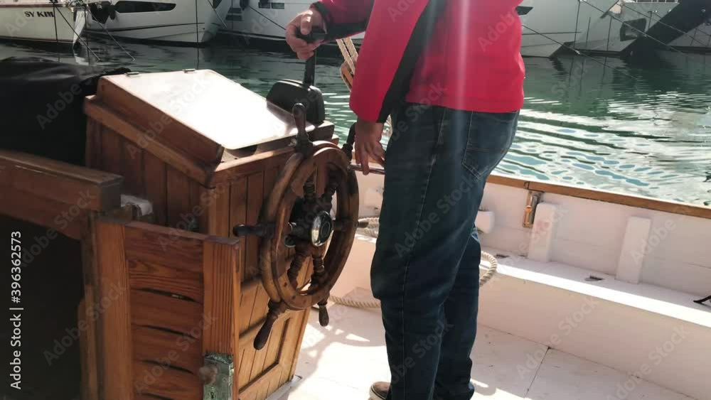 Sailor takes the helm and sails through the port of palma de mallorca in a old boat Sailor takes the helm and sails through the port of palma de mallorca in a old boat