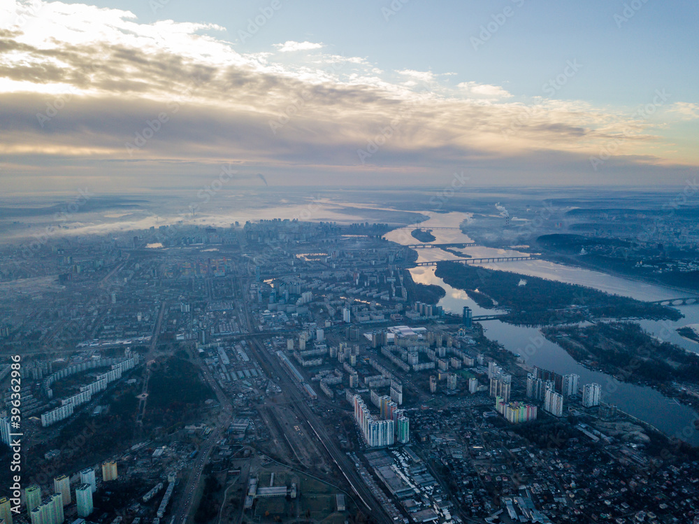 Aerial high flight over Kiev, haze over the city. Autumn morning, the Dnieper River is visible on the horizon.
