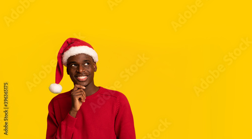 Christmas Gifts Ideas. Pensive Black Guy In Santa Hat Looking Upwards