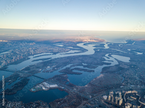 Aerial high flight over Kiev, haze over the city. Autumn morning, the Dnieper River is visible on the horizon. © Sergey