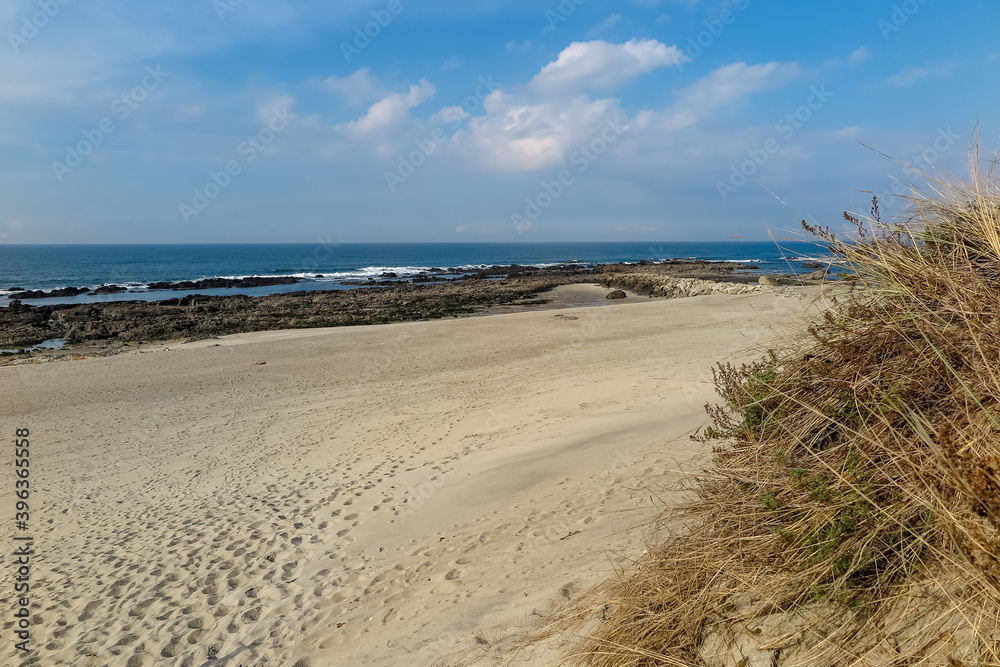 Beaches with clear, fine sand, with low vegetation, blue sea with rocks, cloudless sky, Afife city, parish of Viana do Castelo municipality, NUT III sub-region of Alto Minho, Portugal