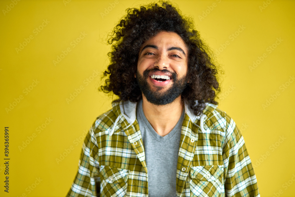 portrait of positive cheerful curly arabian man in casual shirt laughing isolated on green background, young bearded male shine with happiness