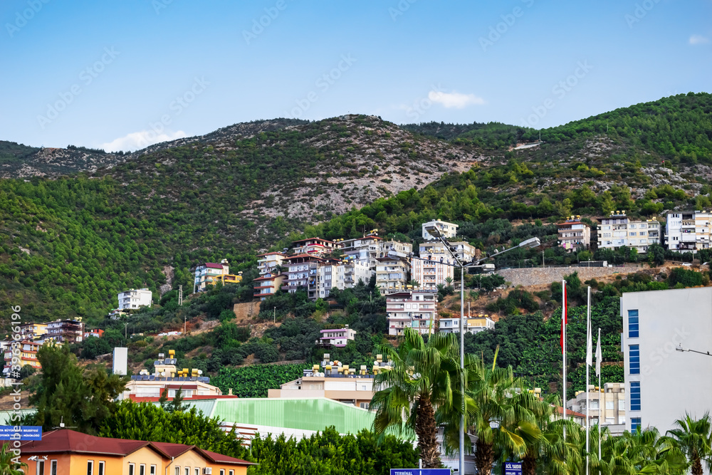 Alanya (Turkey) cityscape with skyscrapers on a mountainside. Tourist Turkish town with banana fields among the mountains