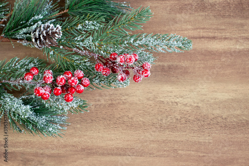 Christmas fir branch with berries and cones  sprinkled with snow on a wooden background close-up with copy space