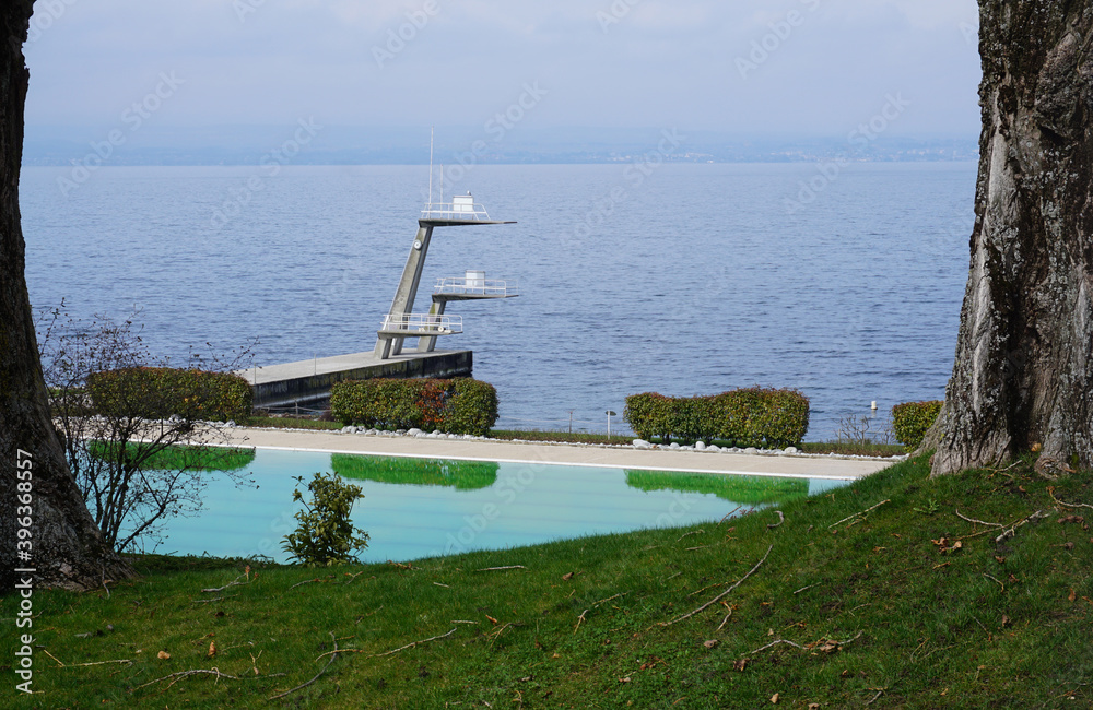 swimming pool with mirror reflection  by Geneva lake in Thonon, France in the park with  diving board