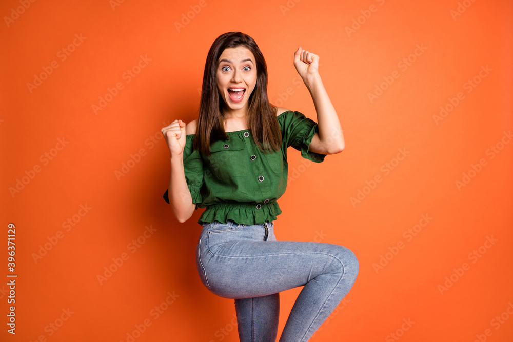 Photo of impressed sweet woman show hands fists wear dark shirt jeans isolated on orange color background Photo of impressed sweet woman show hands fists wear dark shirt jeans isolated on orange color background
