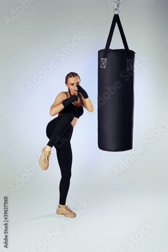 sporty fit woman with boxing bandages in sportswear hitting making kick during boxing exercise on studio background © producer