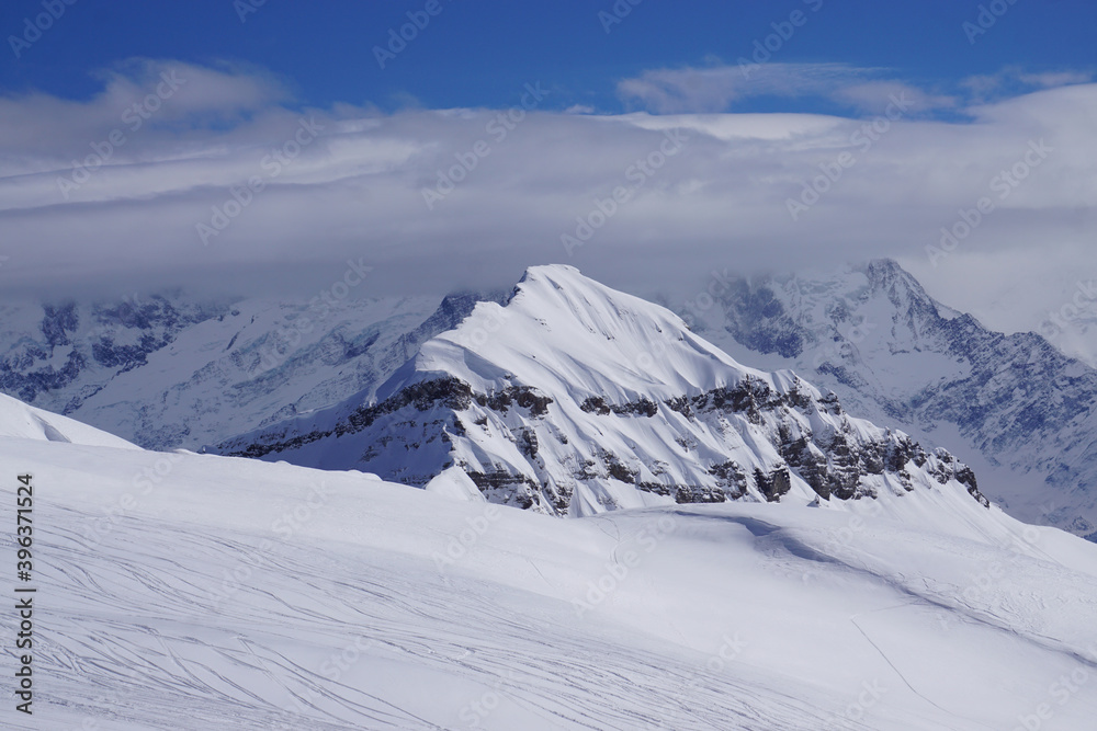 snow covered mountains with clouds and blue sky in the French Alps