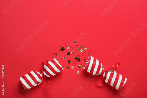 Open Christmas cracker with shiny confetti on red background, top view Tapéta, Fotótapéta
