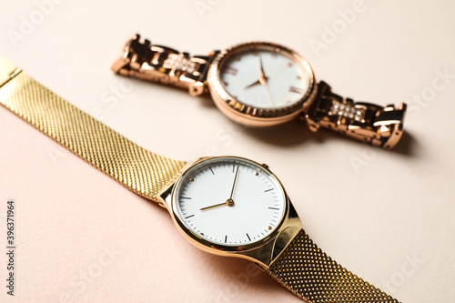 Luxury wrist watches on beige background, closeup