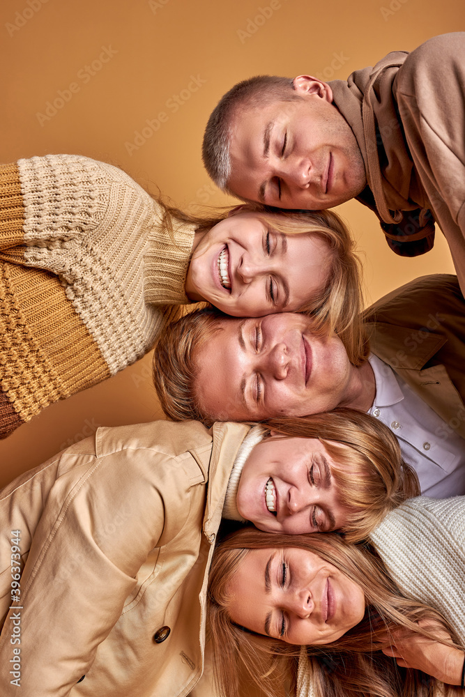portrait of happy dreamy young people isolated in studio with pastel brown background, beautiful males and females lie on heads of each other portrait of happy dreamy young people isolated in studio with pastel brown background, beautiful males and females lie on heads of each other