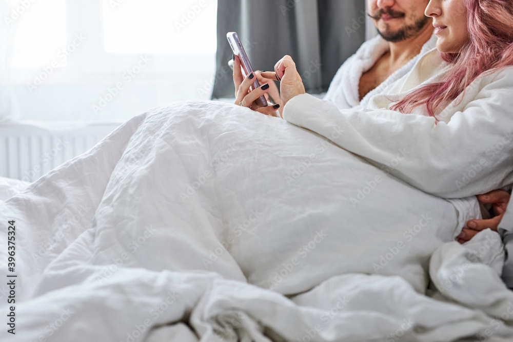 couple with smartphones in pajamas on their bed, caucasian man and woman are searching or browsing over internet and texting in chat with other people, talk couple with smartphones in pajamas on their bed, caucasian man and woman are searching or browsing over internet and texting in chat with other people, talk