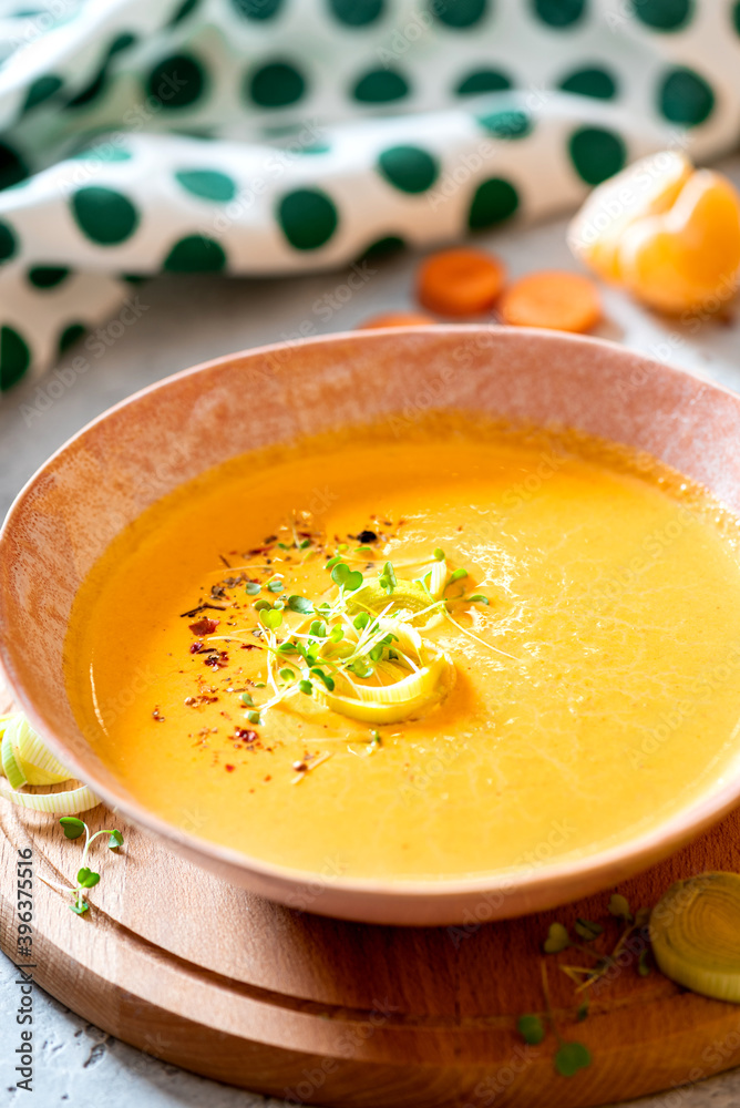 Tasty carrot creamy soup with herbs and spices in a bowl close-up. Soft focus. Autumn or winter food. Pureed vegetable soup. Tasty carrot creamy soup with herbs and spices in a bowl close-up. Soft focus. Autumn or winter food. Pureed vegetable soup.