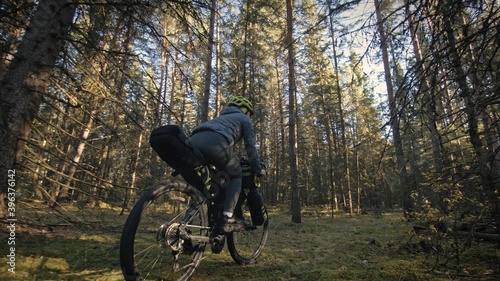 The woman travel on mixed terrain cycle touring with bike bikepacking. The traveler journey with bicycle bags. Magic forest park.