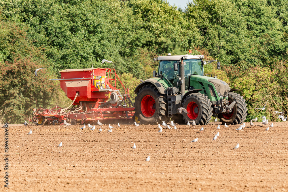 Obraz premium Farmer with tractor and seed drill during sowing and field cultivation - 0811