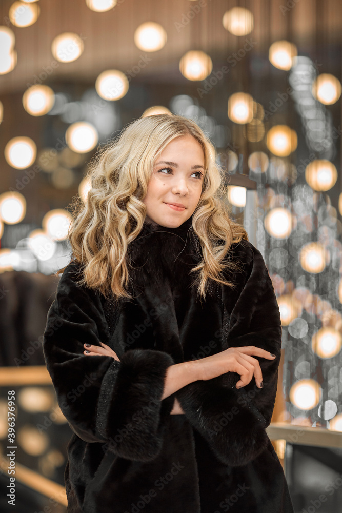 A girl in a black fur coat among the lights of the shopping center A girl in a black fur coat among the lights of the shopping center