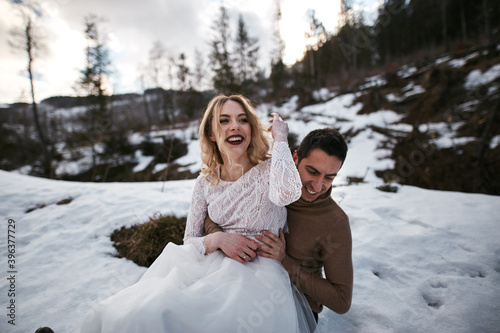 newlywed groom and bride playing in snow. husband hugging his wife in winter forest park. family outdoor activities © AlexGo
