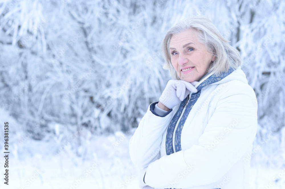 Beautiful senior woman posing in snowy winter park Beautiful senior woman posing in snowy winter park