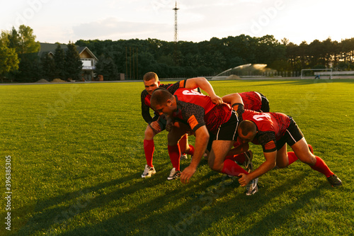 Tableau sur toile A group of men in sports equipment play rugby on a sports field outside
