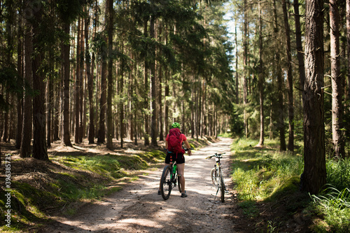 Young woman with helmet riding mountain bicycle in the forest.
