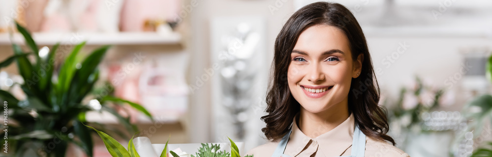  florist looking at camera in flower shop on blurred background, banner