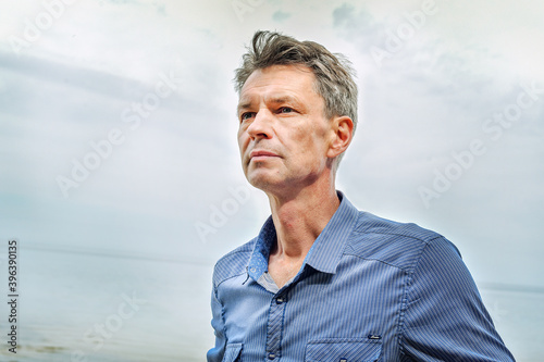 portrait of a man in a shirt near the sea. standing sideways and looking away