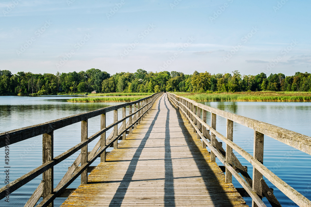 Rustic wooden bridge leading across a wide river. Rustic wooden bridge leading across a wide river.