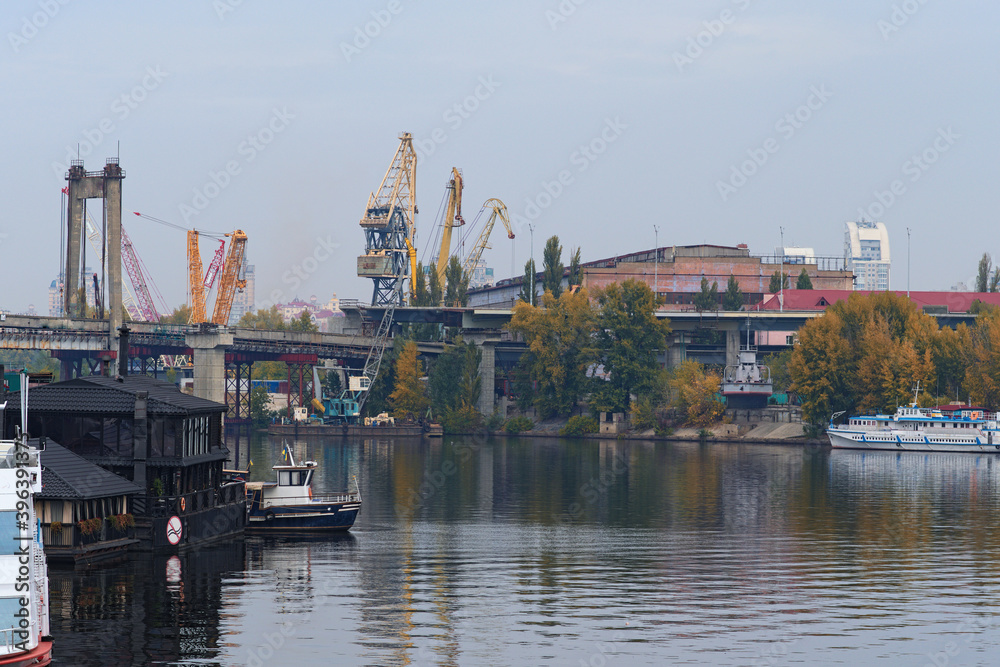 View process of unmounting  an old bridge to the Rybalskyi Island (or  Peninsula). Heavy cranes are used to dismantle bridge structures. Old crane booms in the background