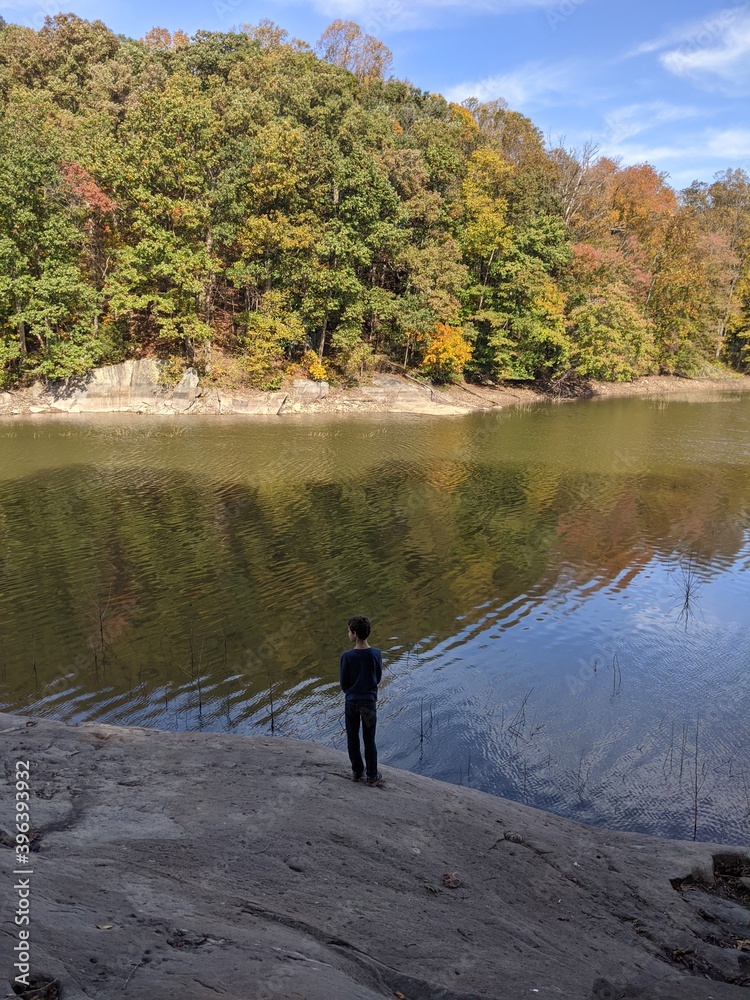 Young boy gazing at peaceful lake in fall. Young boy gazing at peaceful lake in fall.