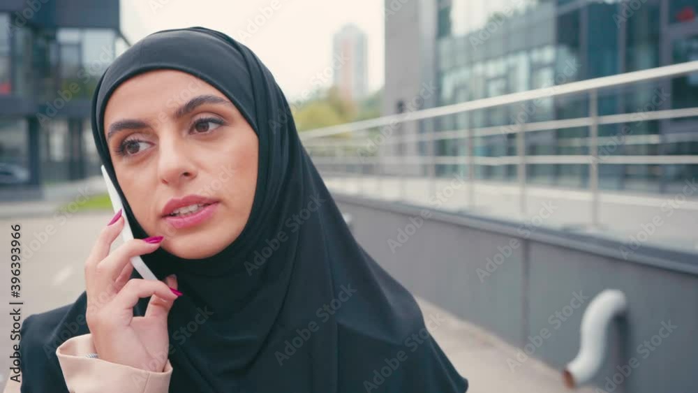 Muslim woman in hijab talking on smartphone outdoors Muslim woman in hijab talking on smartphone outdoors