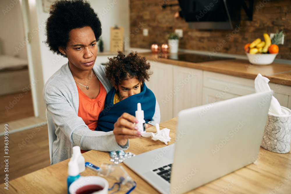Φωτογραφία African American mother consulting online with family doctor while being with her ill daughter at home