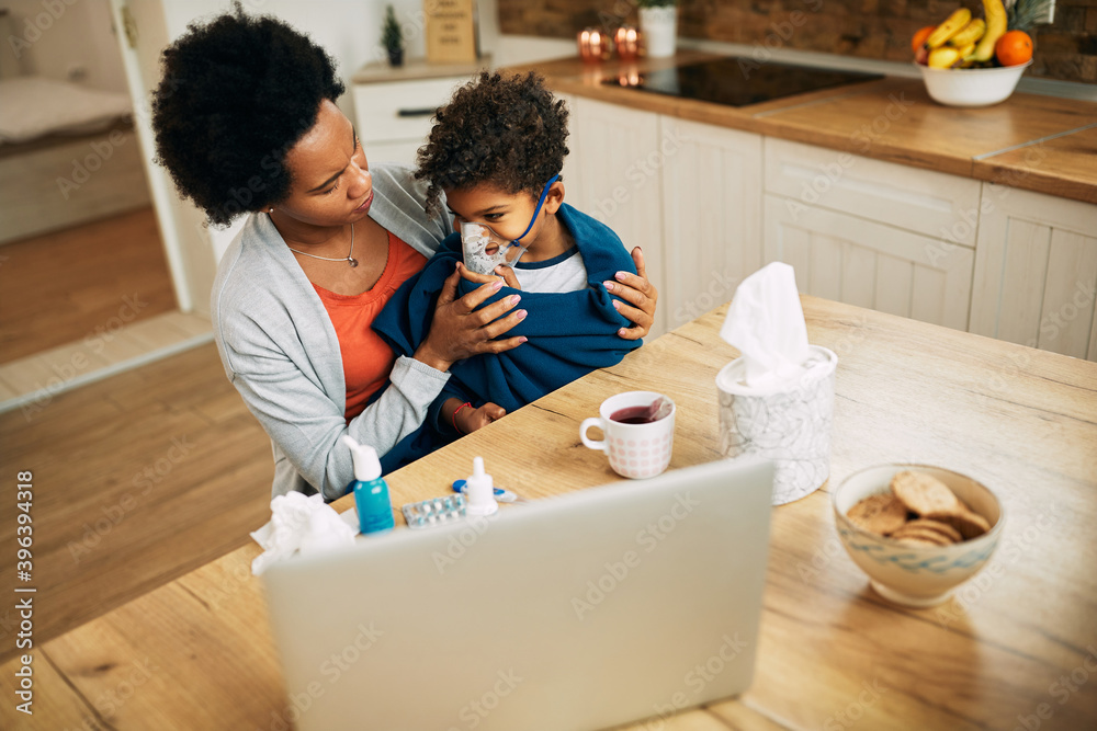 African American mother giving her sick son asthma treatment at home. African American mother giving her sick son asthma treatment at home.