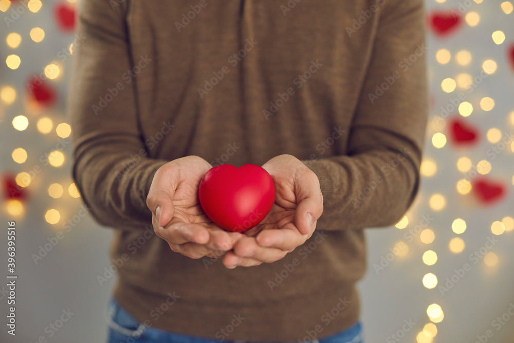 Male hands holding decorated red heart as symbol of love