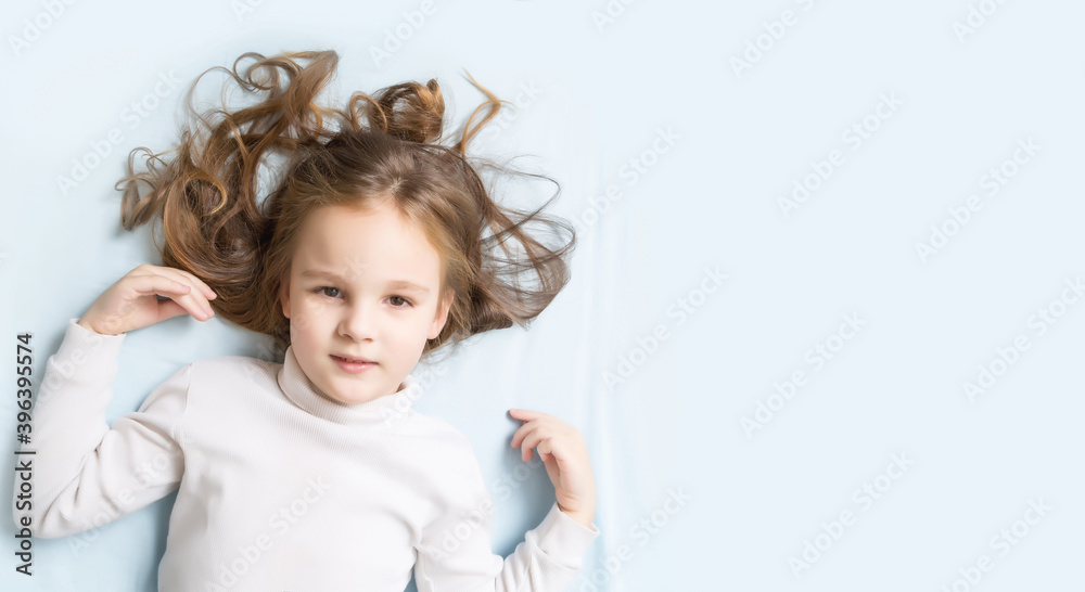 Little brunette girl lying sweetly in bed with blue linen. space for text. healthy baby's sleep. top view. Kid long curly hair fall asleep pillow close up. happy childhood Little brunette girl lying sweetly in bed with blue linen. space for text. healthy baby's sleep. top view. Kid long curly hair fall asleep pillow close up. happy childhood