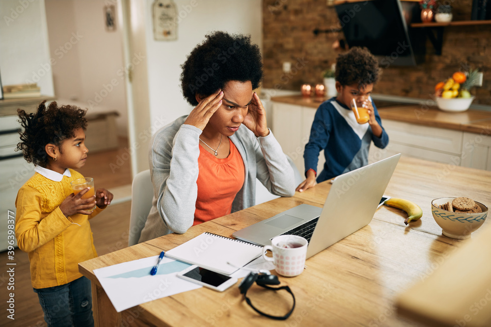 Frustrated African American single mother working on laptop at home