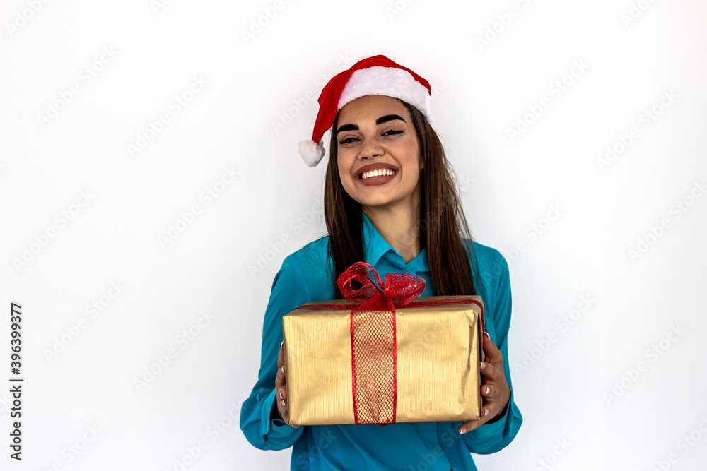 Portrait of young happy smiling woman holding a gift box wrapped in golden paper with red ribbon over white background. Happy Caucasian girl standing isolated over white background, holding a gift box Portrait of young happy smiling woman holding a gift box wrapped in golden paper with red ribbon over white background. Happy Caucasian girl standing isolated over white background, holding a gift box