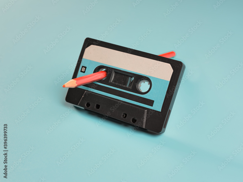 Fototapeta premium Vintage audio cassette and pencil on blue background